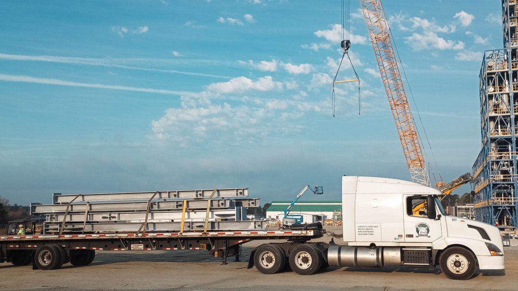 Image: IRF Transport flatbed shipping truck being loaded with steel construction materials.